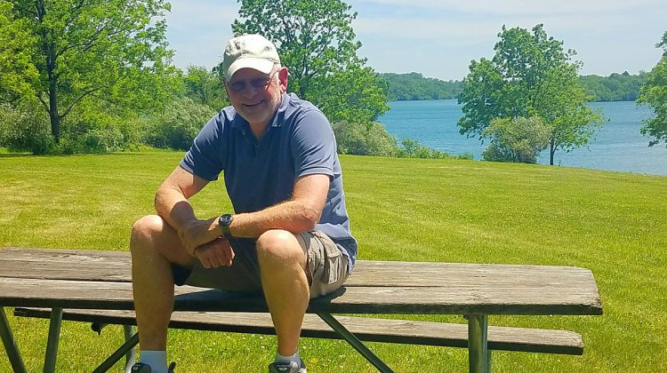 man sitting on bench near lake